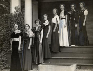 Black and white image of eight women in long dresses standing on the steps of a building