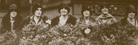 Black and white image of six women in 1920s style hats carrying evergreen wreaths