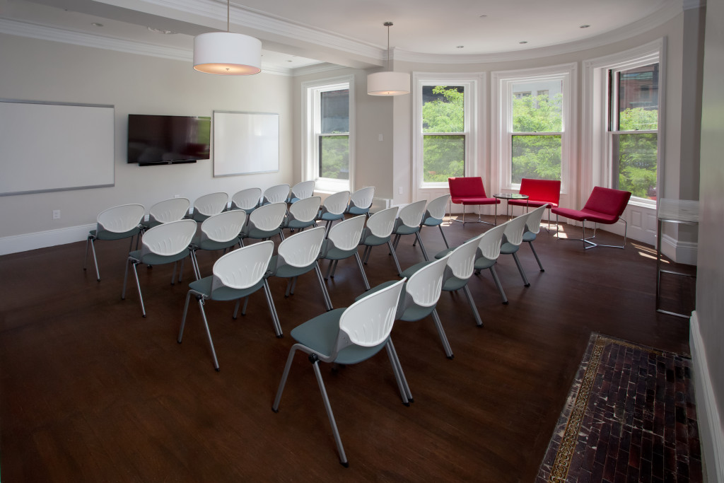 Image of the training room, featuring four rows of chairs facing a set of white boards and a large television monitor