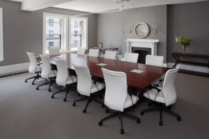 Image of a board room, featuring business chairs around a large meeting table