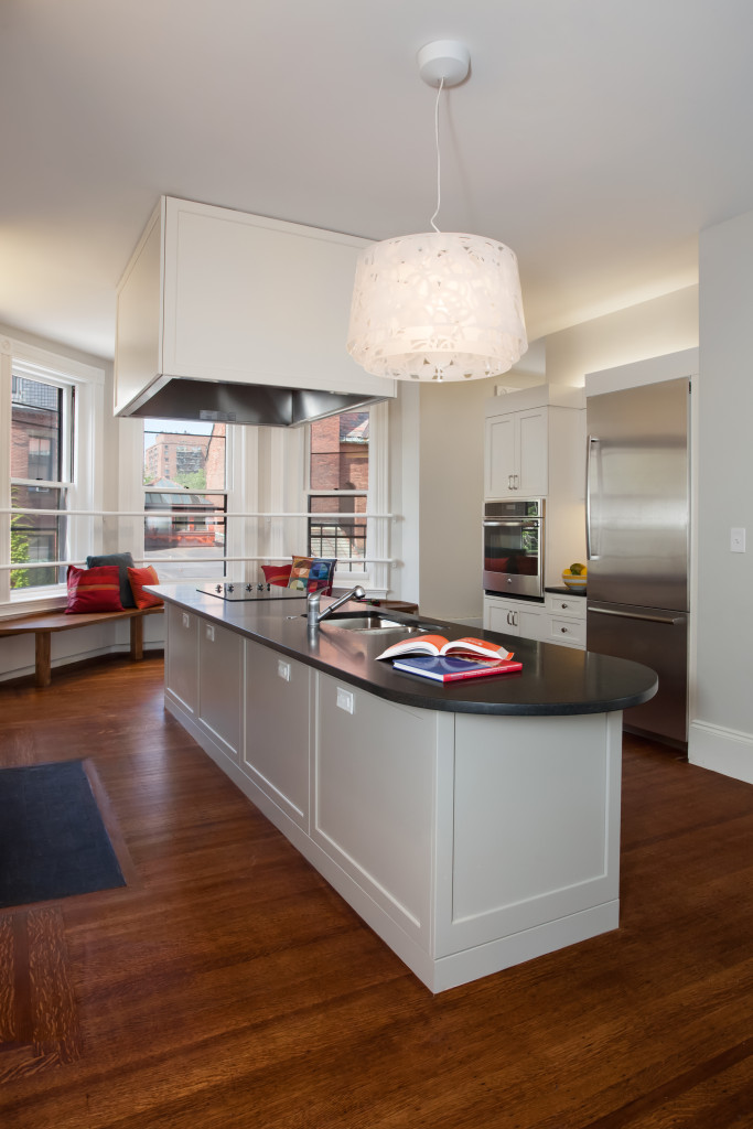 Image of a kitchen with a wall oven, a refrigerator, and a kitchen island with sink