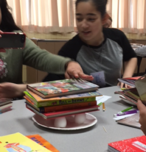 A STEM program participant tests how many books can be stacked on eggshells before they crack.